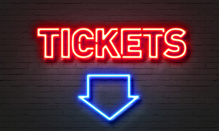 Red neon lettered TICKETS sign mounted on brick wall with blue neon arrow pointed down at picture caption.