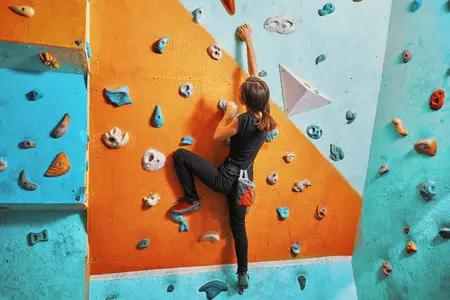 Young woman climbing a colorful indoor rock wall at AZ on the Rocks.